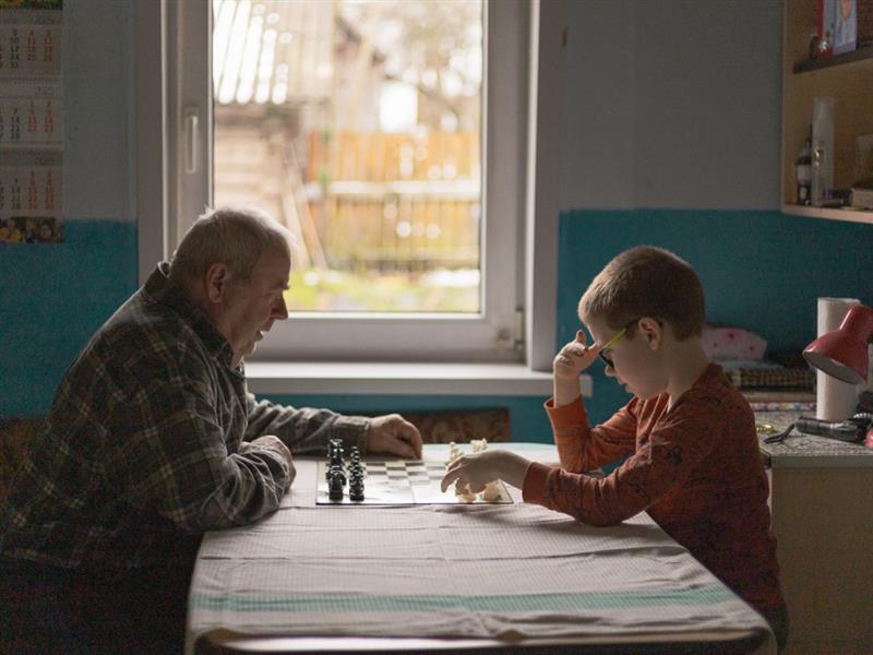 boy and elderly man playing chess
