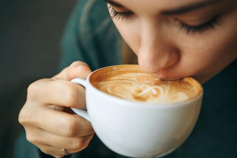 A girl drinks coffee from a cup.
